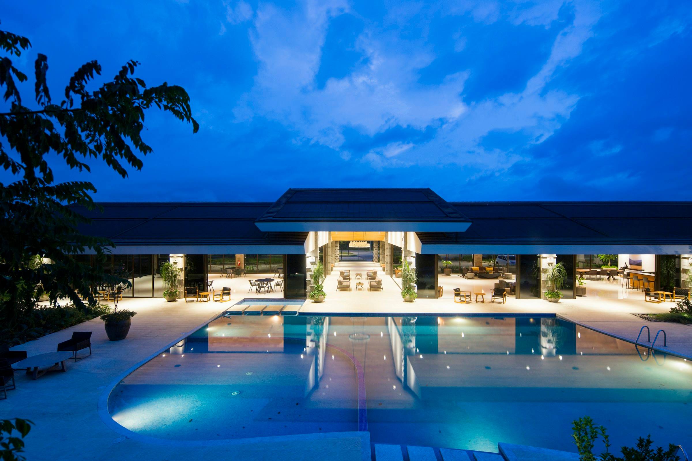 Resort hotel facade and pool at dusk, palm trees silhouetted against the evening sky